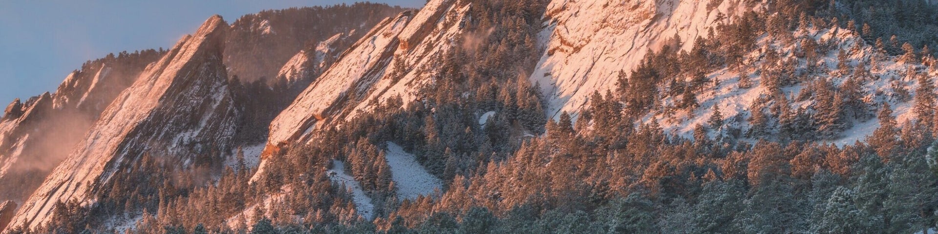 A snow-covered mountain range with dense forests at its base.