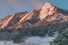 A snow-covered mountain range with dense forests at its base.