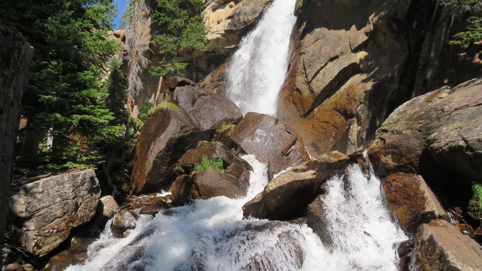 Ouzel Falls spills over a cliffside and enormous boulders, making it arguably one of the most beautiful waterfalls in Rocky Mountain National Park. Before reaching this 40-foot falls, the trail traces the course of several creeks and leads hikers past three other cascade waterfalls. A moderate 5.4 miles round trip hike