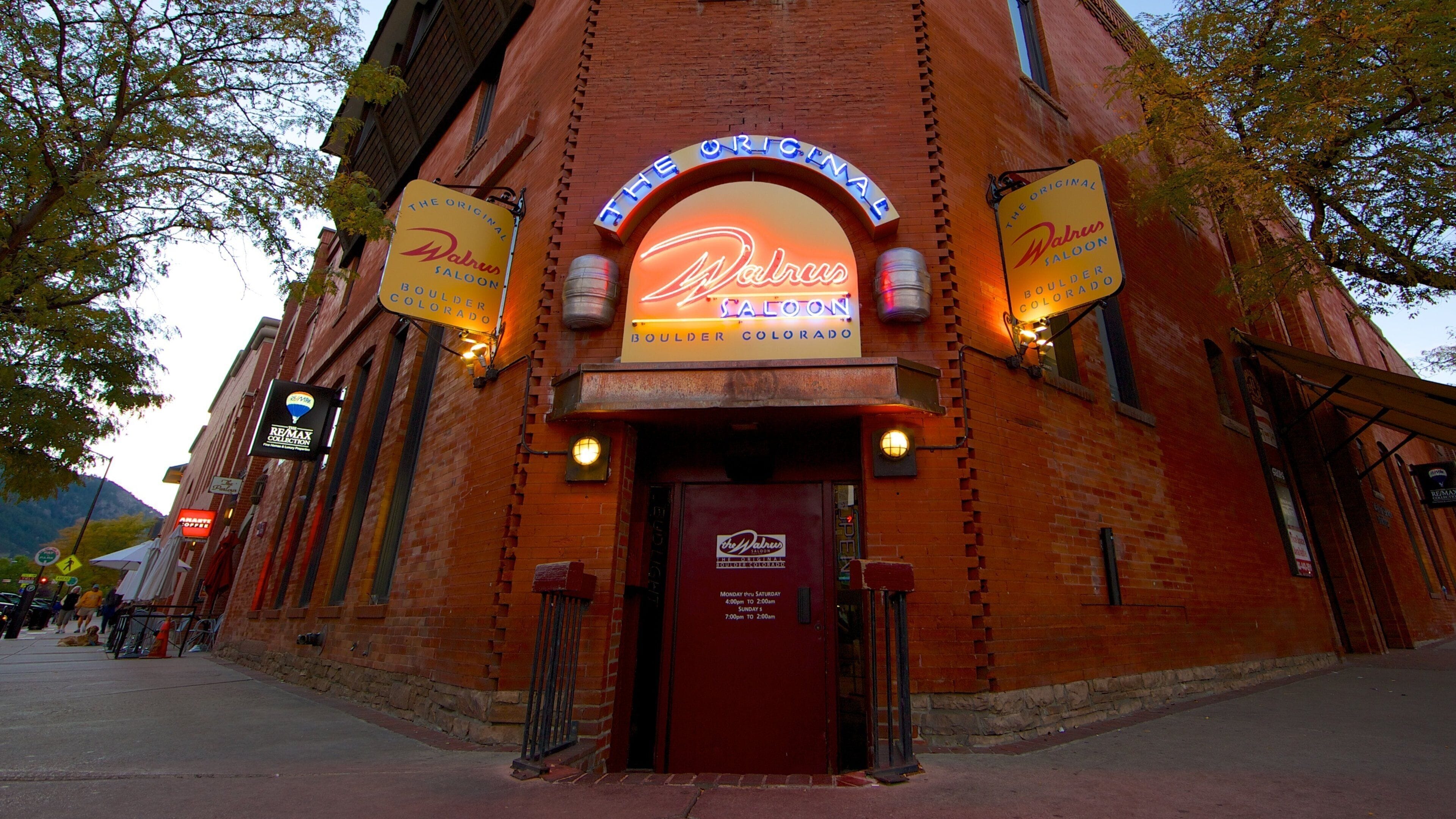 A brick building with neon signs for 'The Original Walrus Saloon' and 'The Original Boulder Colorado'.