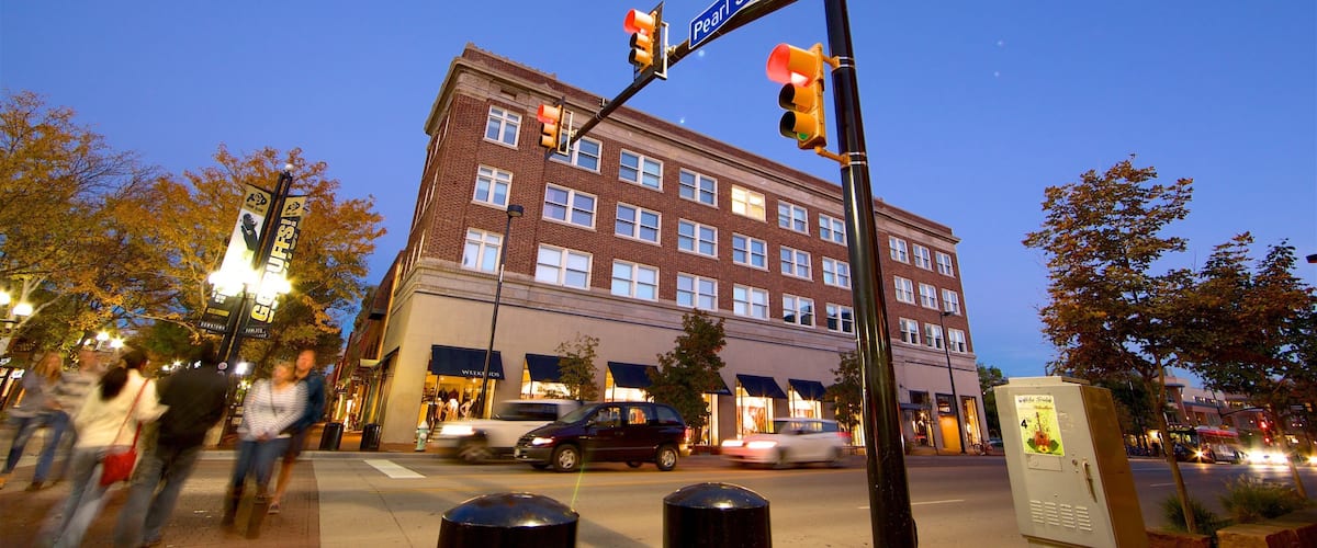 A street corner with a traffic light, a street sign reading "Pearl St Mall 1900", and a brick building with multiple windows.