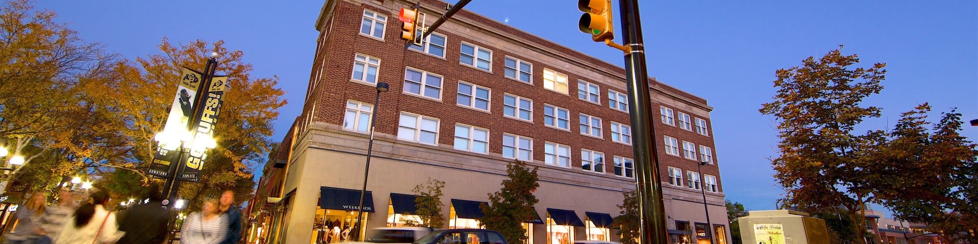 A street corner with a traffic light, a street sign reading "Pearl St Mall 1900", and a brick building with multiple windows.