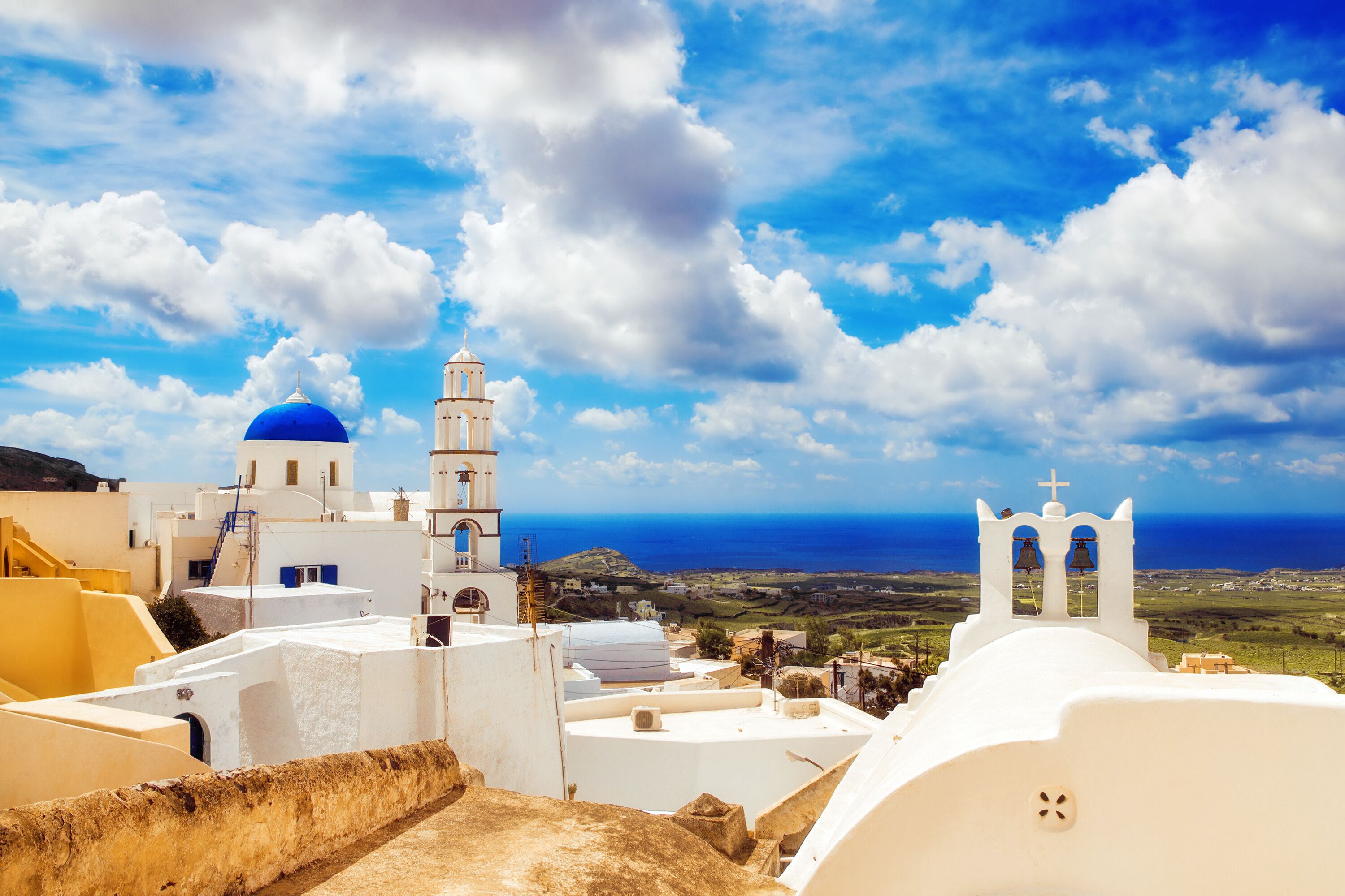 A coastal town with white buildings, a blue dome, and a bell tower.