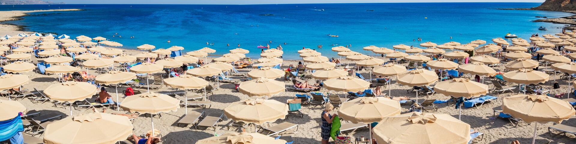 Kiotari beach with umbrellas and holiday-makers in village of Kiotari - PANORAMA (Rhodes, Greece)