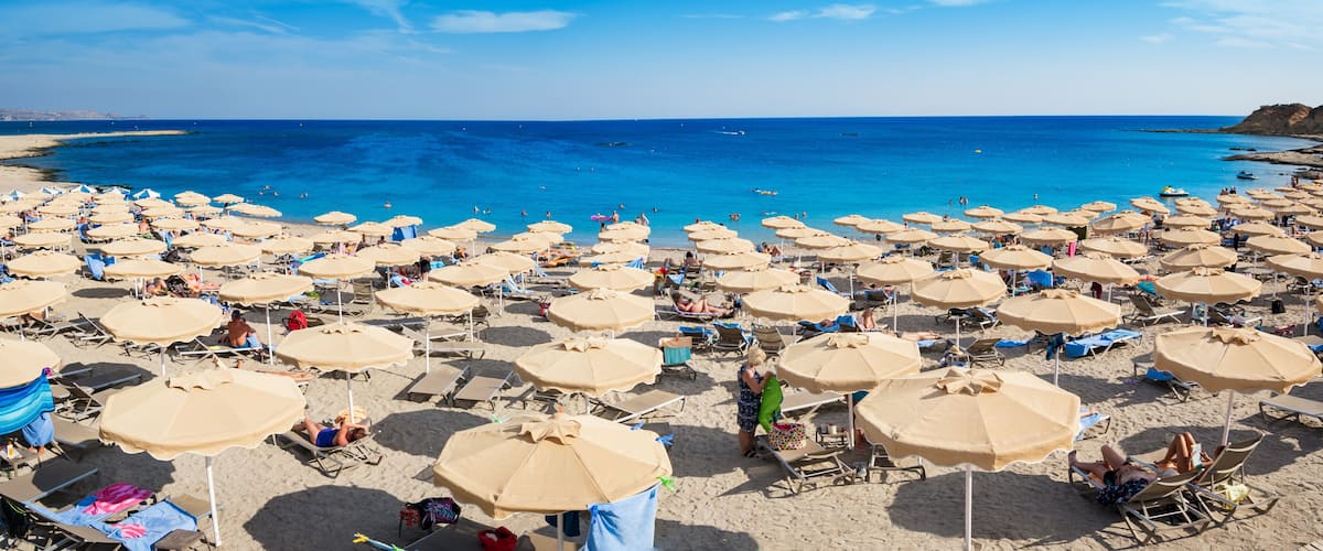 A beach with numerous sun umbrellas and lounge chairs.