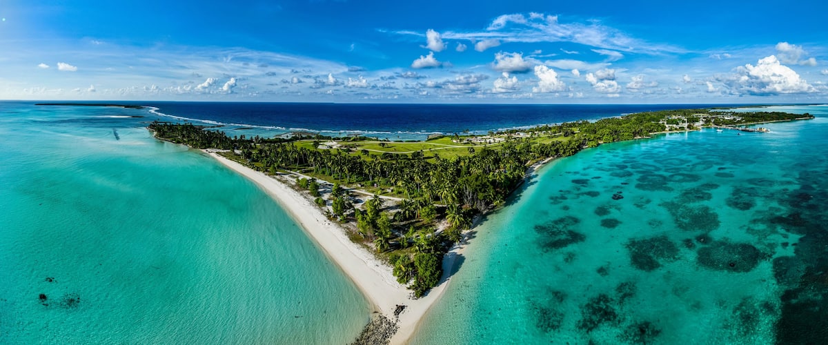 A tropical island with clear turquoise waters, a white sandy beach, and lush greenery.