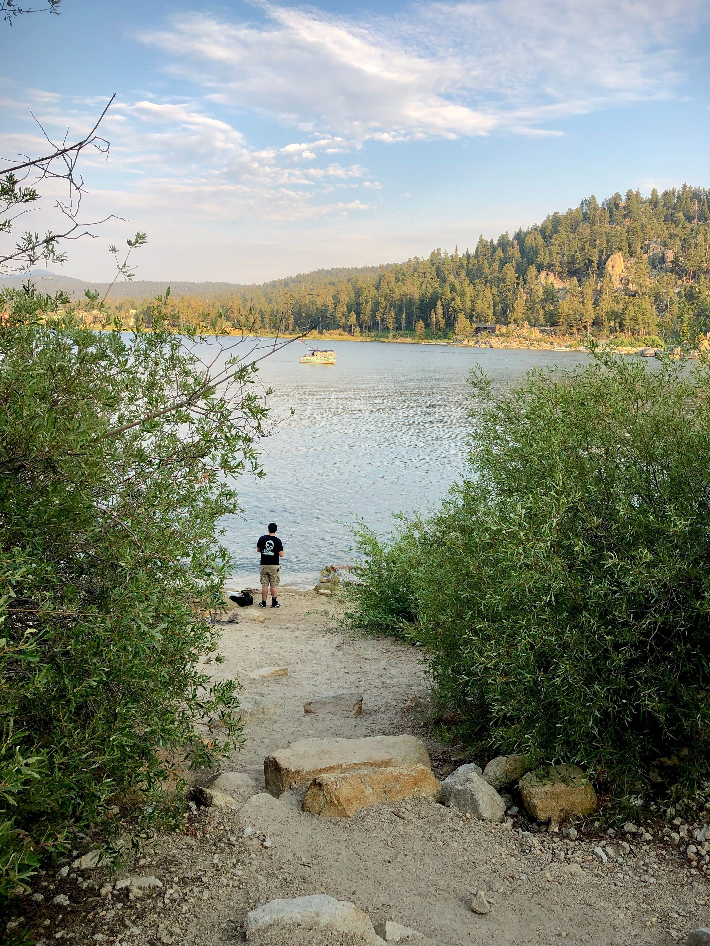 A little fishing on the sandy northern shores of Big Bear Lake in summer, with views of the cabins of Boulder Bay, perched precariously on cliffs, in the distance.