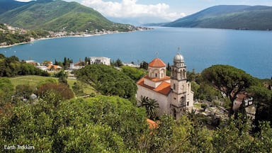 Uma vila costeira com uma igreja imponente, vegetação exuberante e uma grande extensão de água.