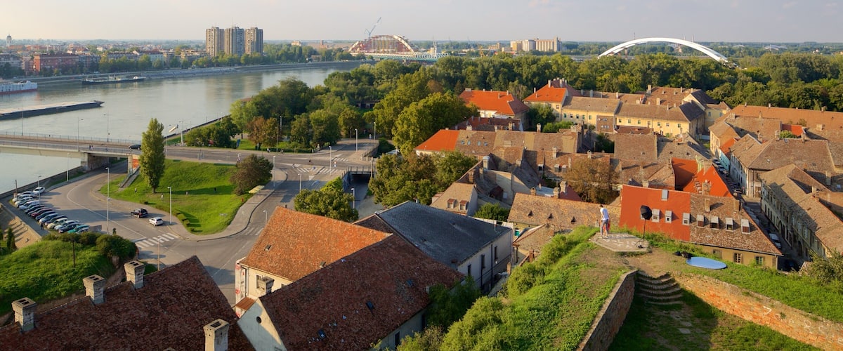Un pueblo a orillas del río con edificios históricos, un puente y un puente moderno de arco.