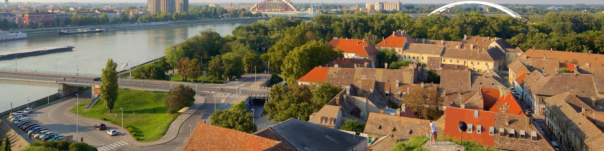 A riverside town with historic buildings, a bridge, and a modern arch bridge.