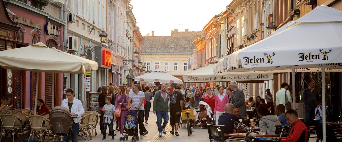 A crowded street with outdoor cafes, people walking, and bicycles parked.