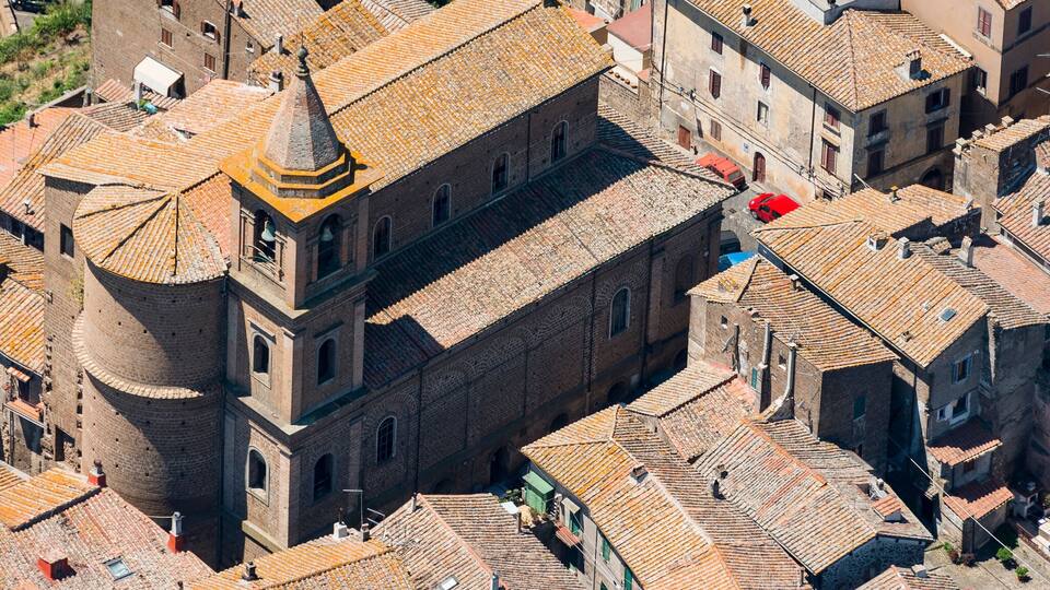 An aerial view of a densely packed historic town with closely built structures, prominent brick buildings, and a central tower.