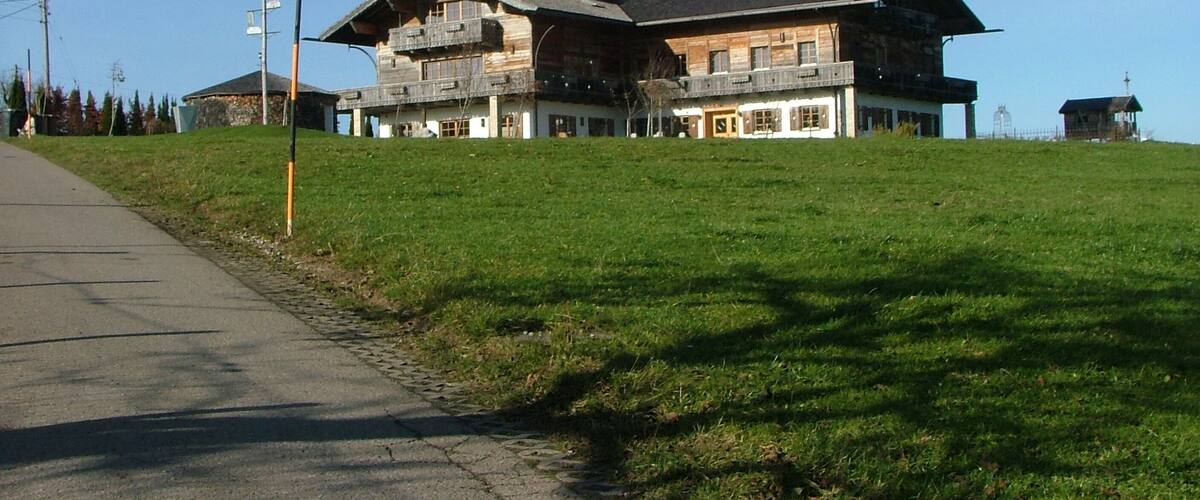 A large wooden chalet with balconies, set on a grassy hillside.