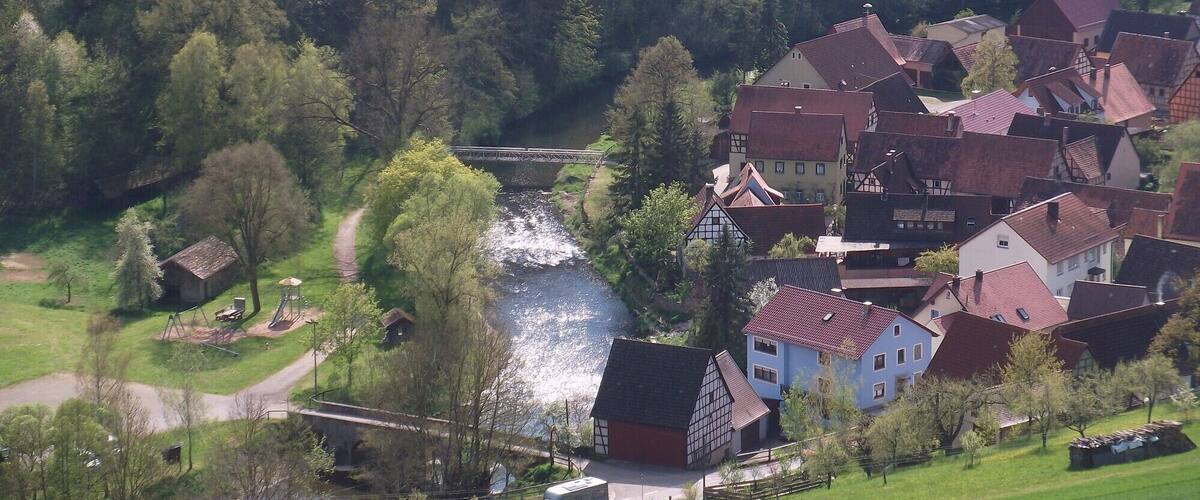A river flowing through a village with traditional houses and a bridge.