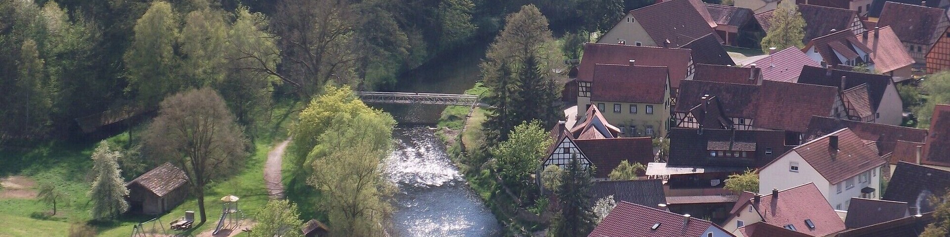 A river flowing through a village with traditional houses and a bridge.