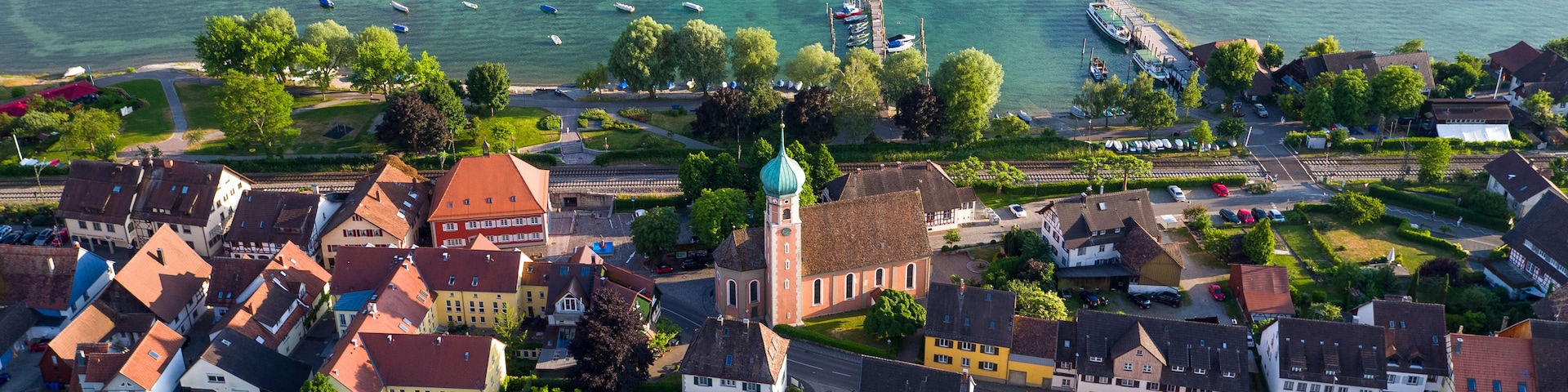 Uma cidade costeira com uma igreja, edifícios residenciais e uma marina com barcos.