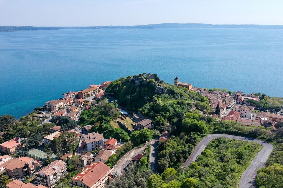 A coastal town with a prominent hilltop church and dense greenery.