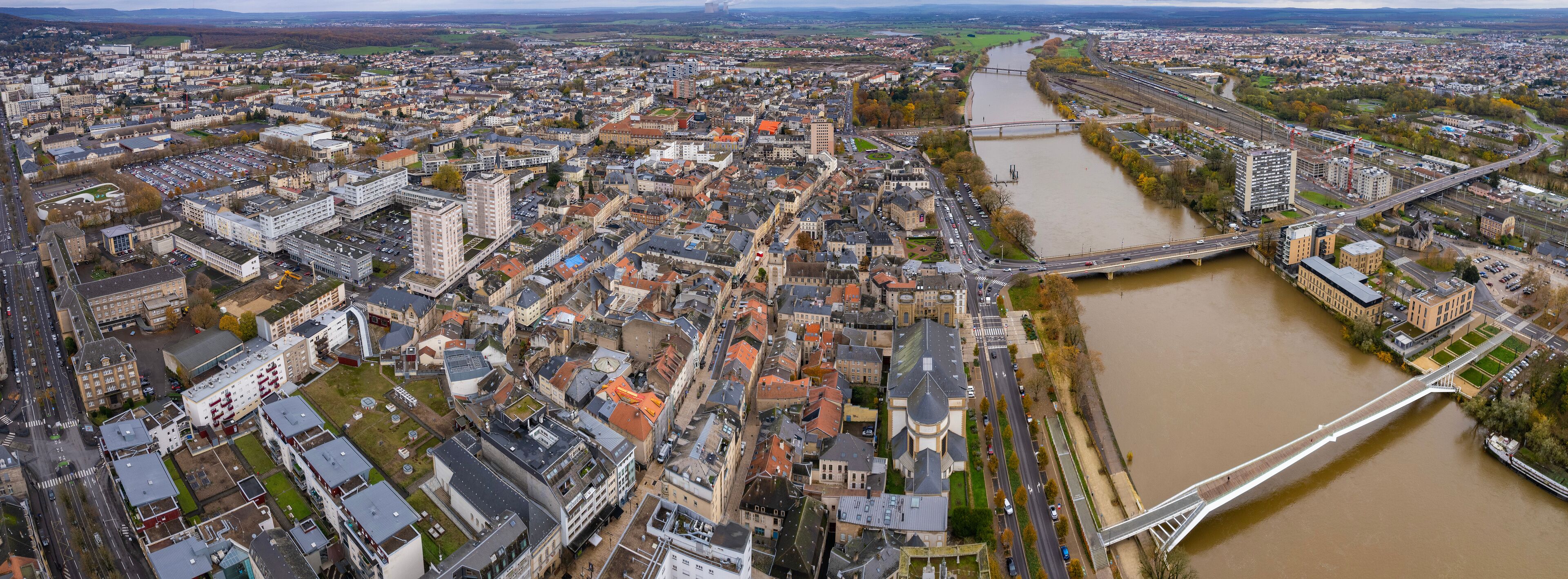 An aerial view of a city with a river, a bridge, and surrounding buildings.