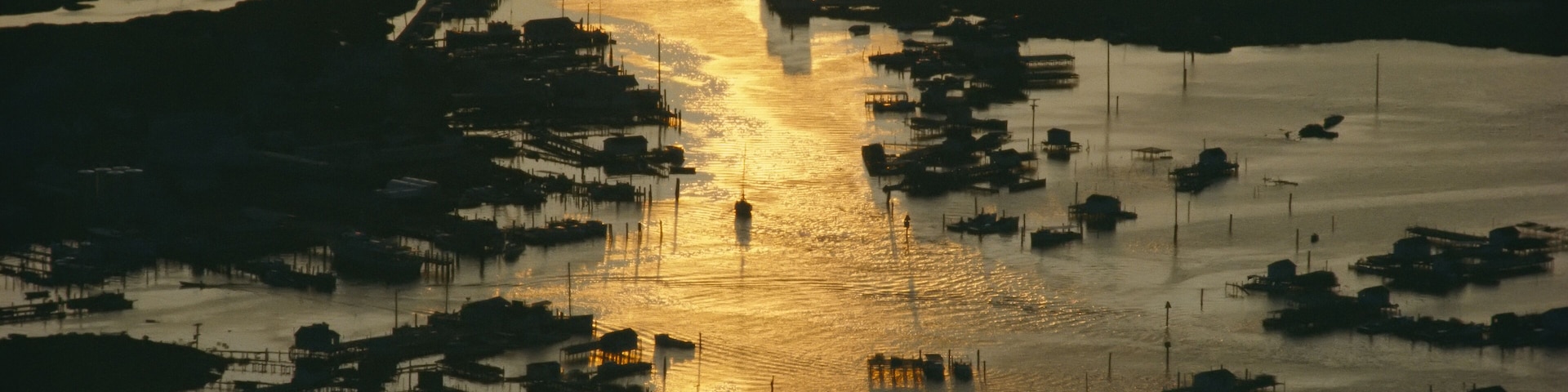 Un atardecer sobre una vía fluvial con numerosos barcos y edificios.