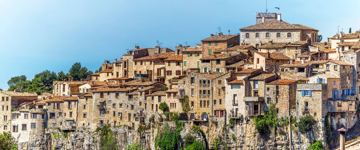 A historic stone village with terracotta roofs perched on a cliff.