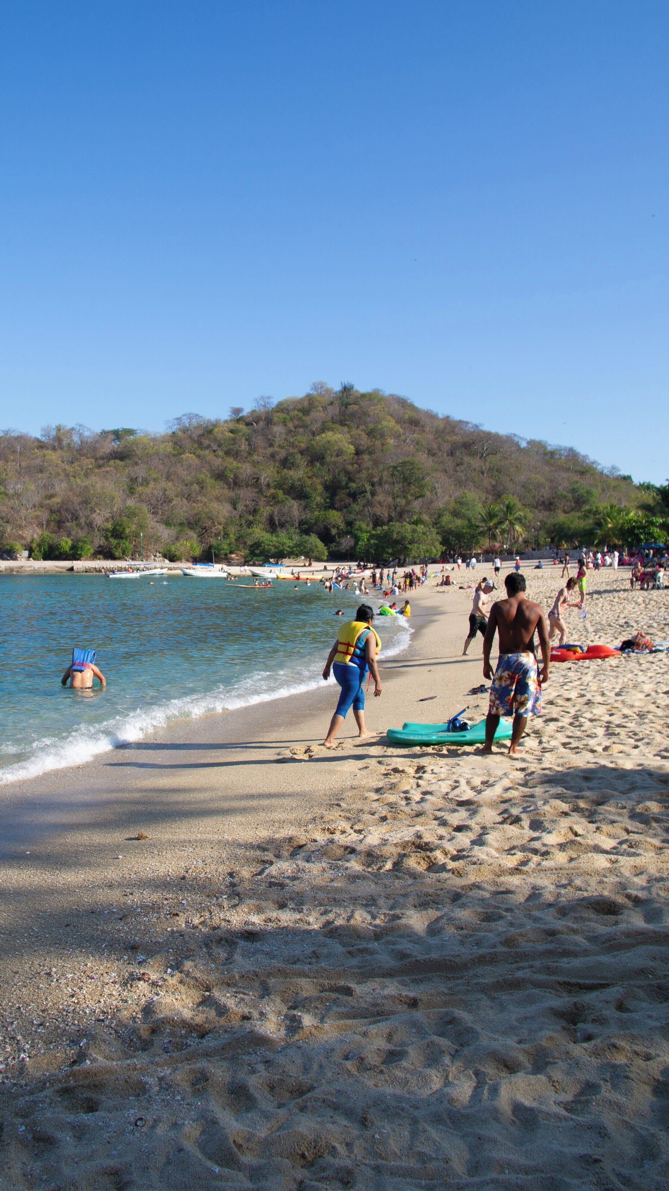 Relaxing day at La Entrega Beach in Santa Maria Huatulco, Mexico with families enjoying sun, sand, and water activities