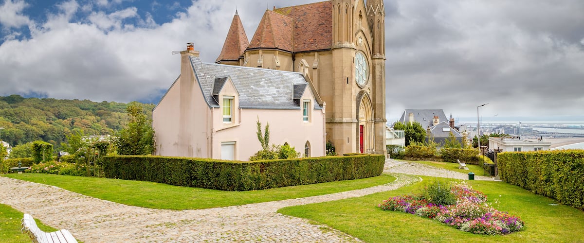 A church with a clock tower, a cobblestone path, and a bench.