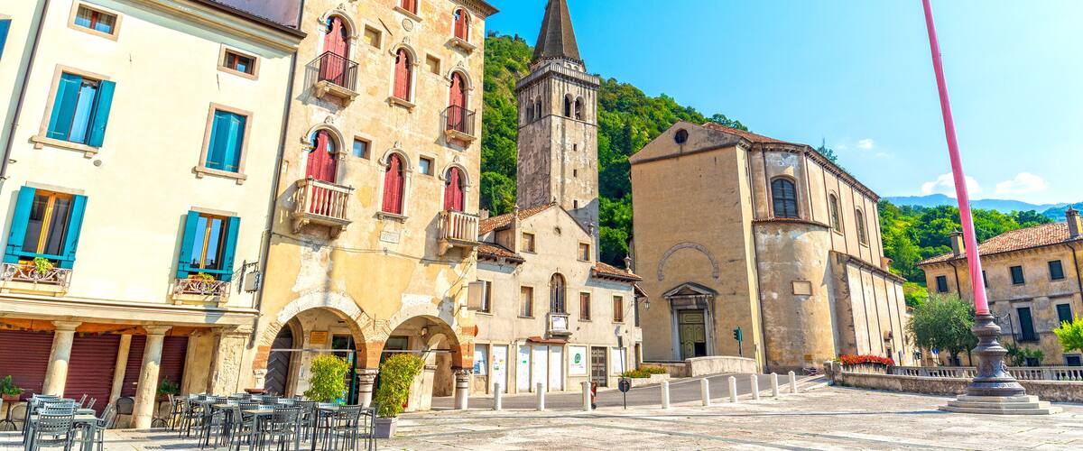 A historic town square with a church tower, traditional buildings, and outdoor seating.
