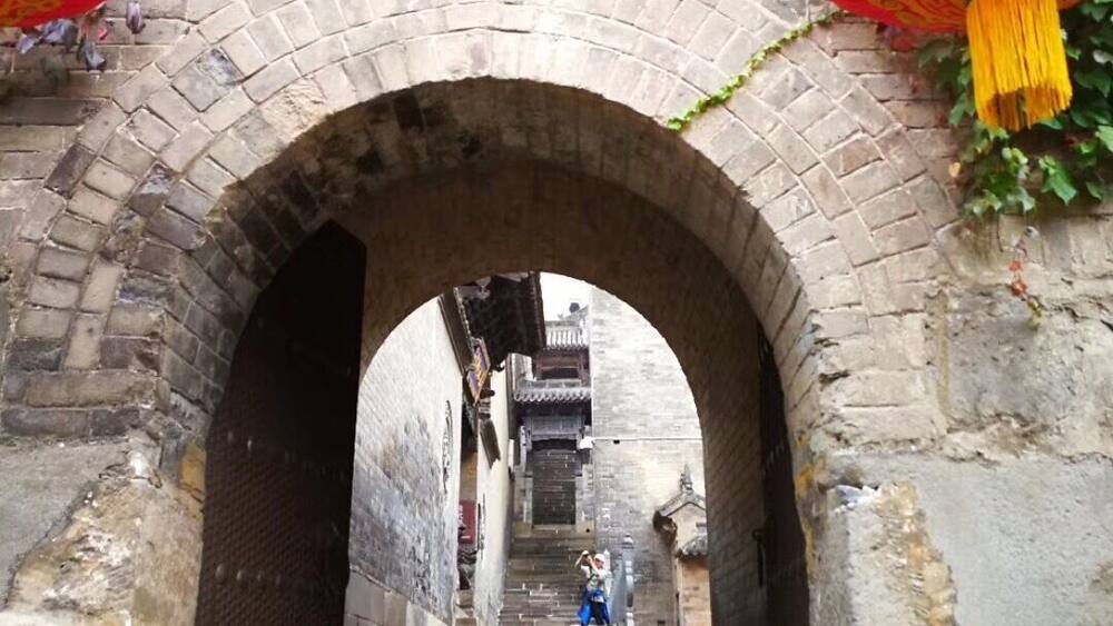 An arched stone bridge with red lanterns and a sign above.
