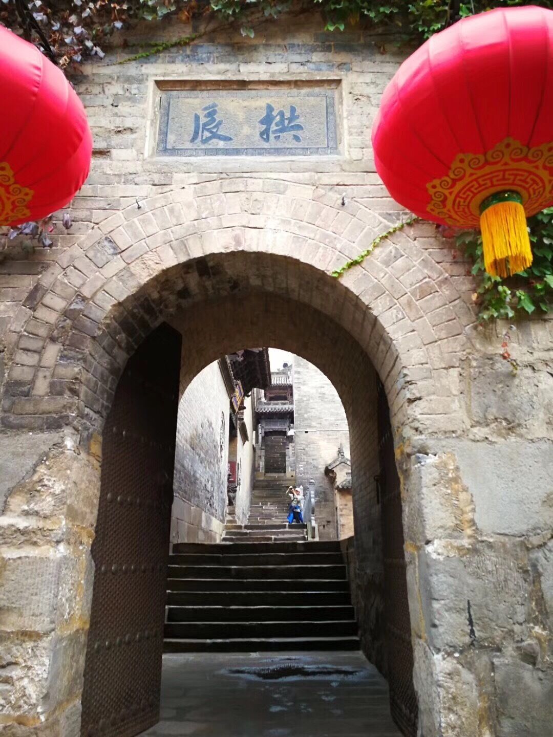 An arched stone bridge with red lanterns and a sign above.