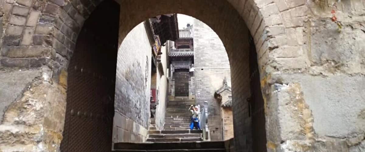 An arched stone bridge with red lanterns and a sign above.