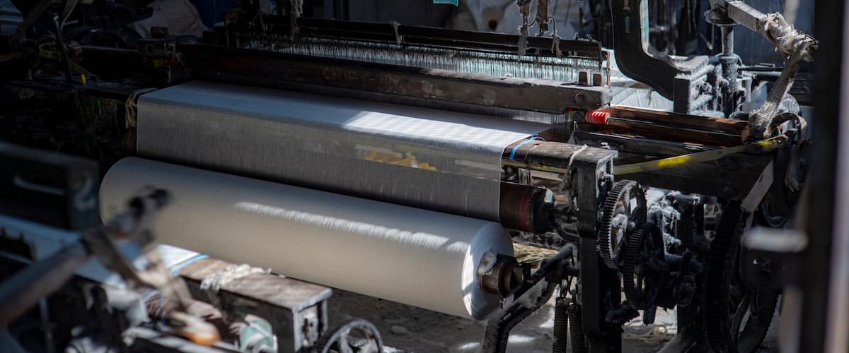 A textile machinery with large rolls of fabric and mechanical components.
