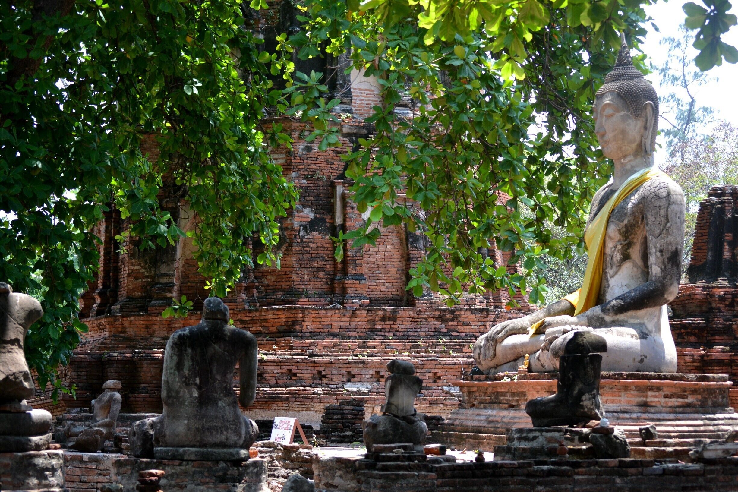 A large seated Buddha statue surrounded by smaller stone statues in a temple setting.