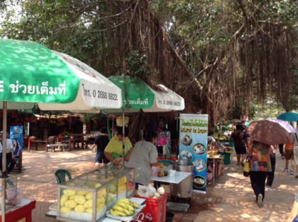 A market stall with a green umbrella and a sign in a foreign language.