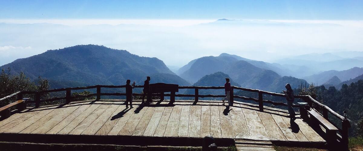 A wooden viewing platform overlooking a mountain range with a clear sky.