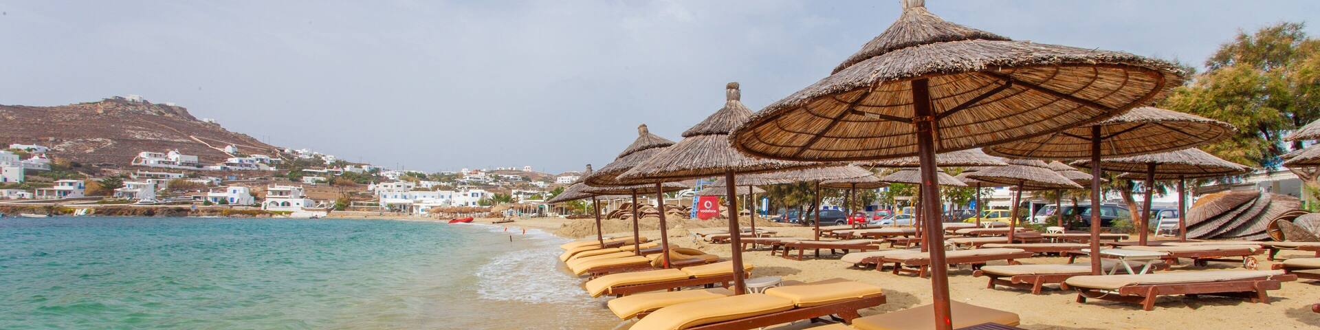 A beach with sun loungers and thatched umbrellas.
