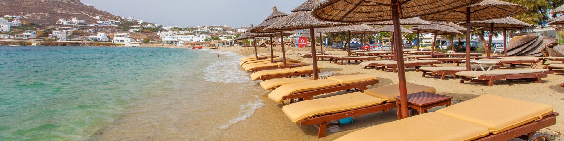 Una playa con tumbonas y sombrillas de paja.