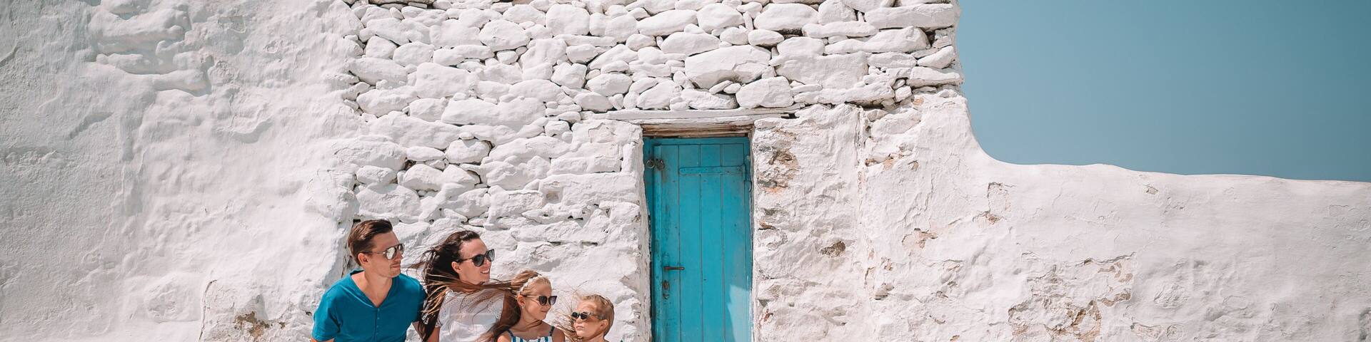 Parents and kids at street of typical greek traditional village on Mykonos Island, in Greece