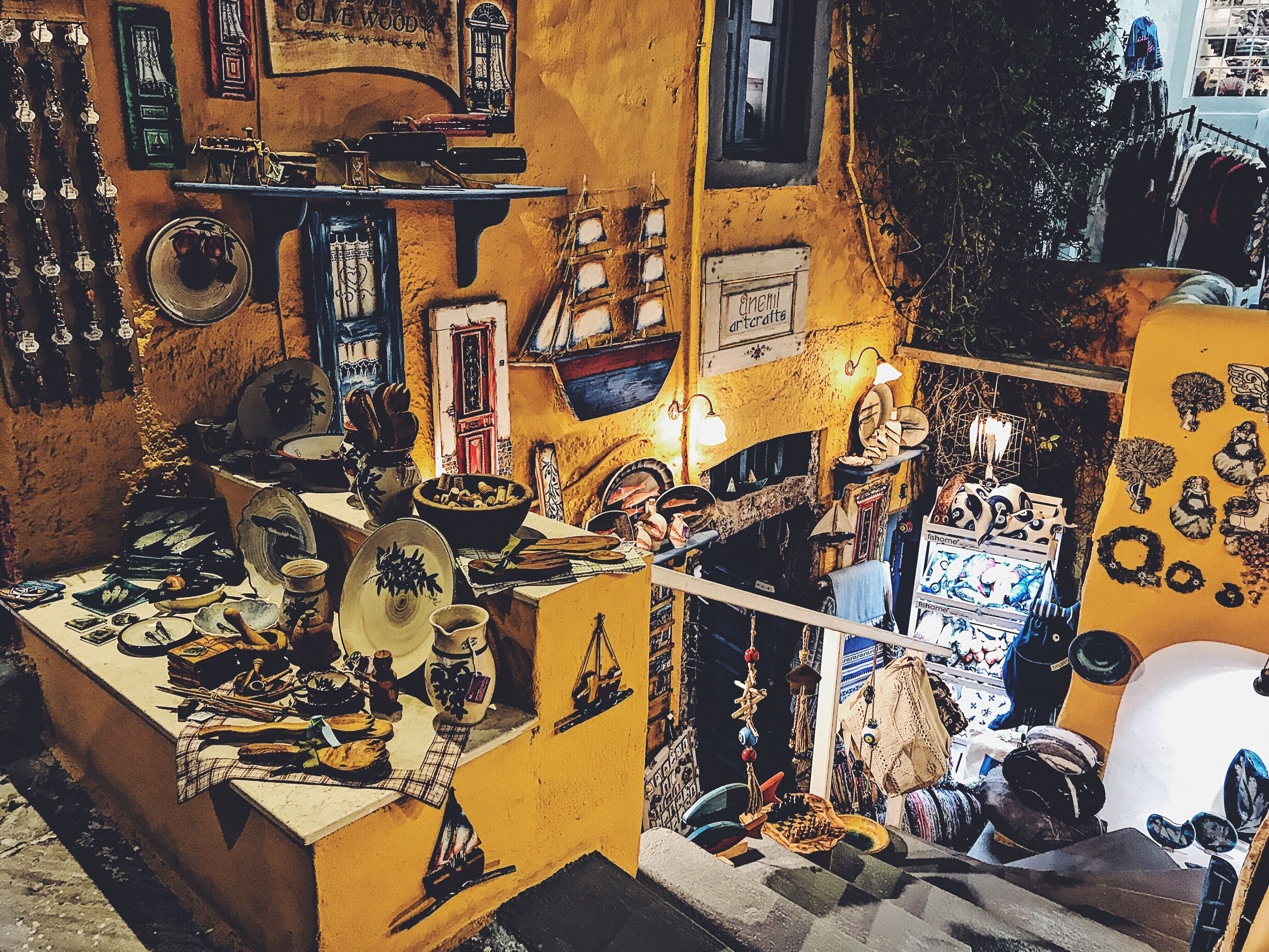 Una tienda llena de objetos variados, incluyendo cerámica, textiles y adornos colgantes.
