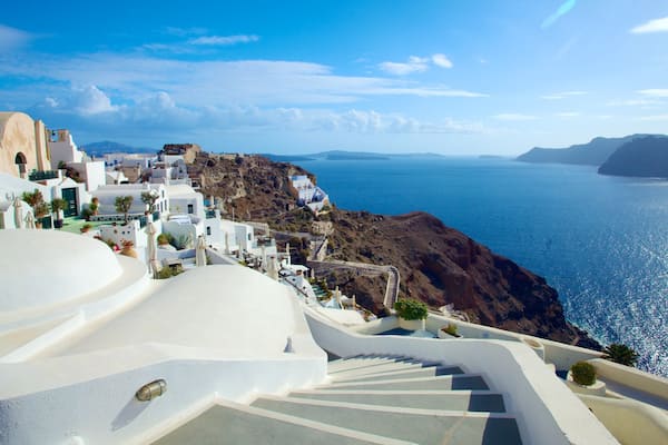 A coastal town with white-washed buildings, a rocky coastline, and a clear blue sea.