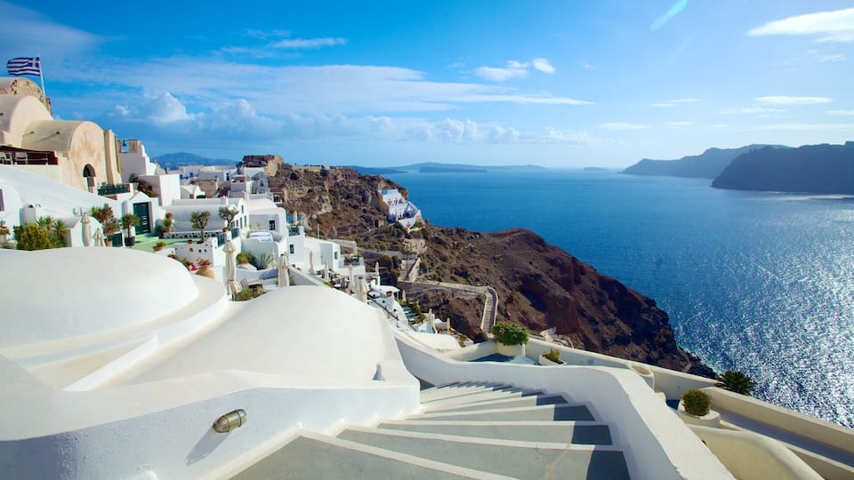 A coastal town with white-washed buildings, a rocky coastline, and a clear blue sea.