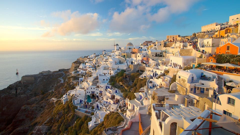 A coastal village with white-washed buildings, a windmill, and a view of the sea.