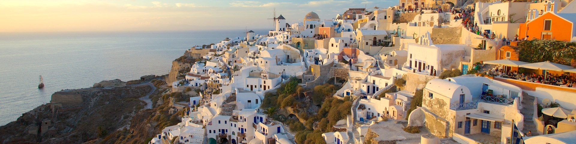 A coastal village with white-washed buildings, a windmill, and a view of the sea.