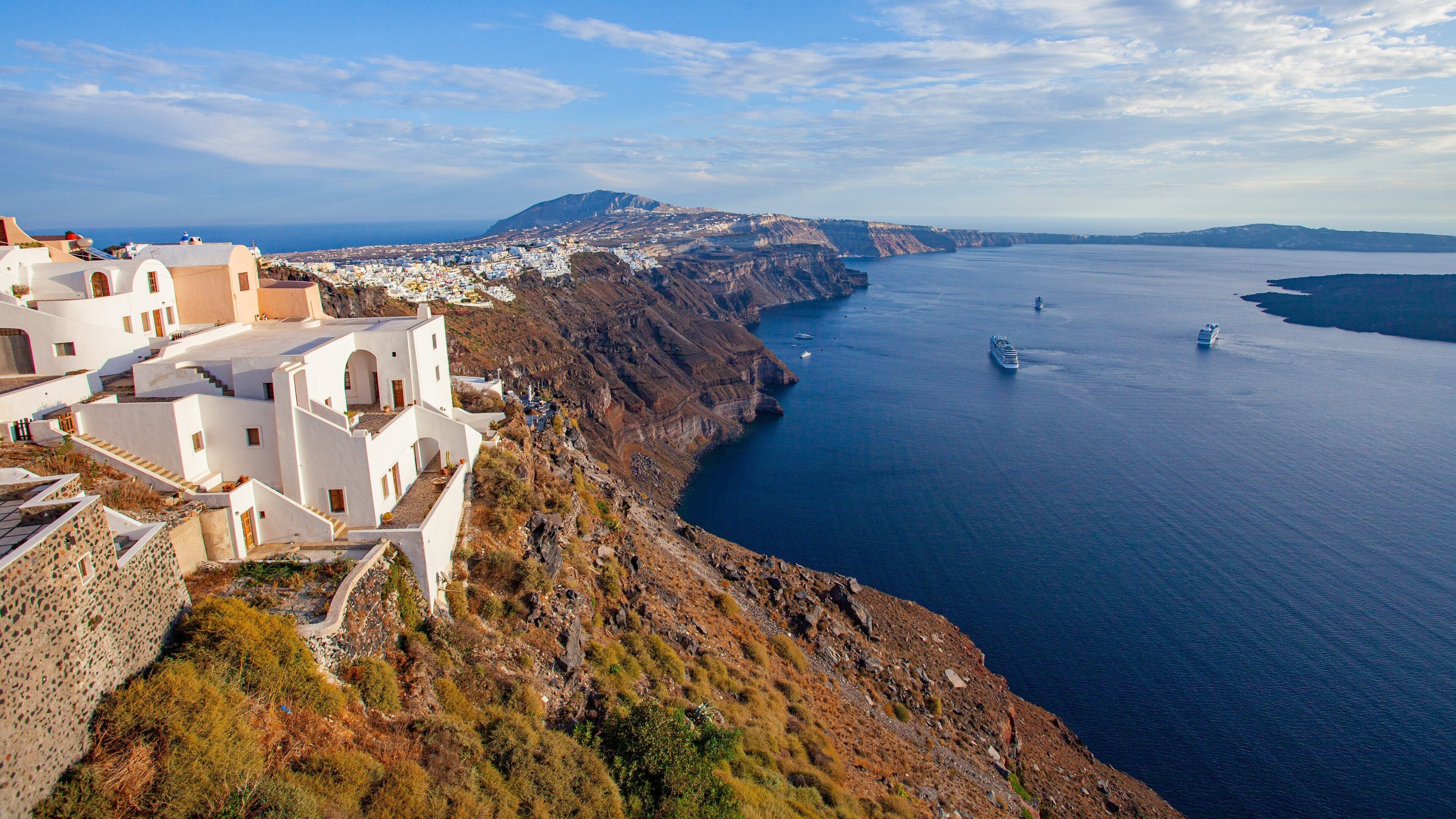 Un pueblo costero con edificios blancos, un litoral rocoso y un barco en el mar.