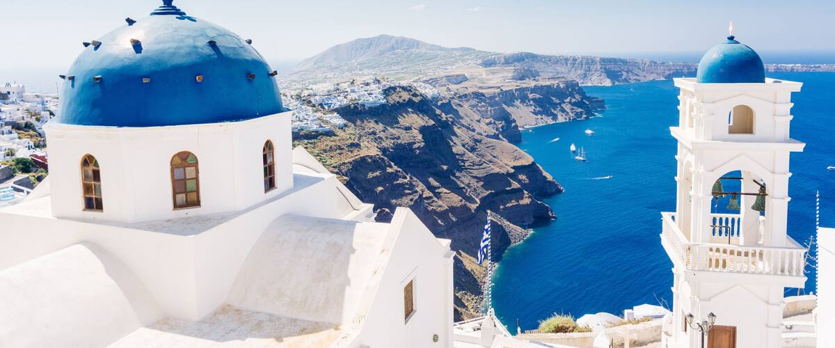 Beautiful blue dome church and view of voclanic caldera in Imerovigli, village on Santorini island, Greece