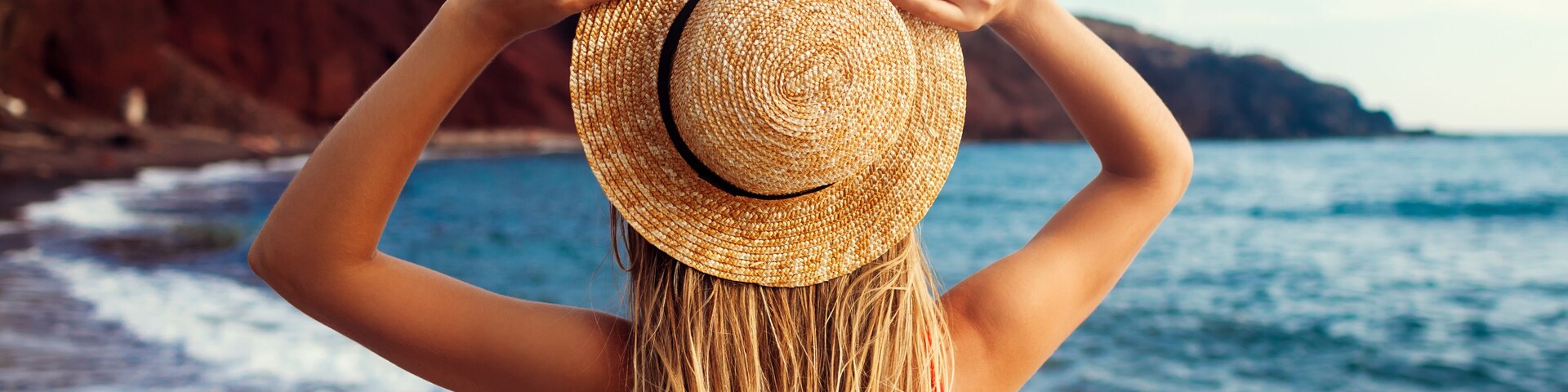 Sexy woman in bikini relaxing on Red beach in Santorini, Greece. Girl enjoying sea and mountain landscape