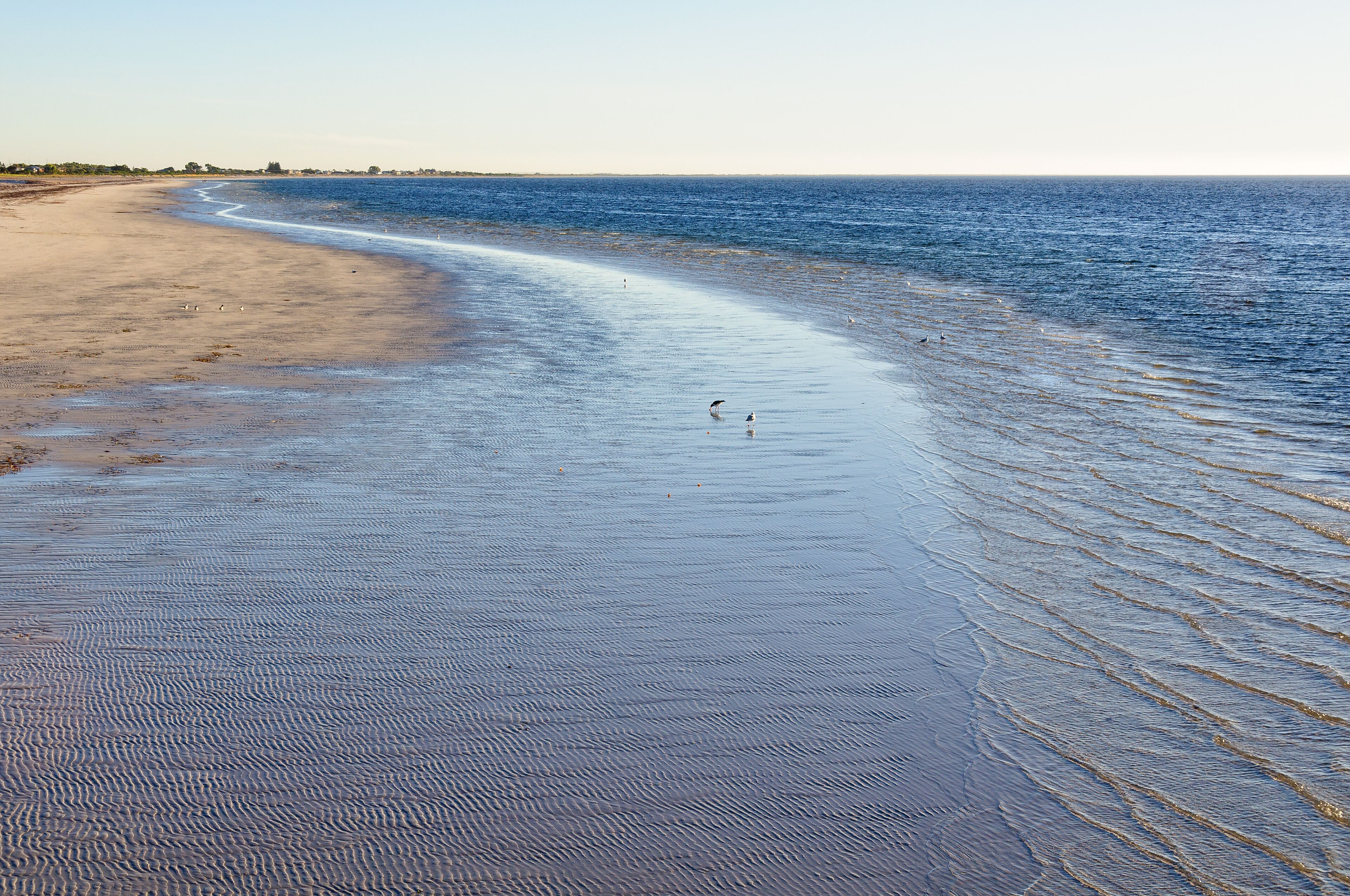 A wide sandy beach with gentle waves lapping at the shore.