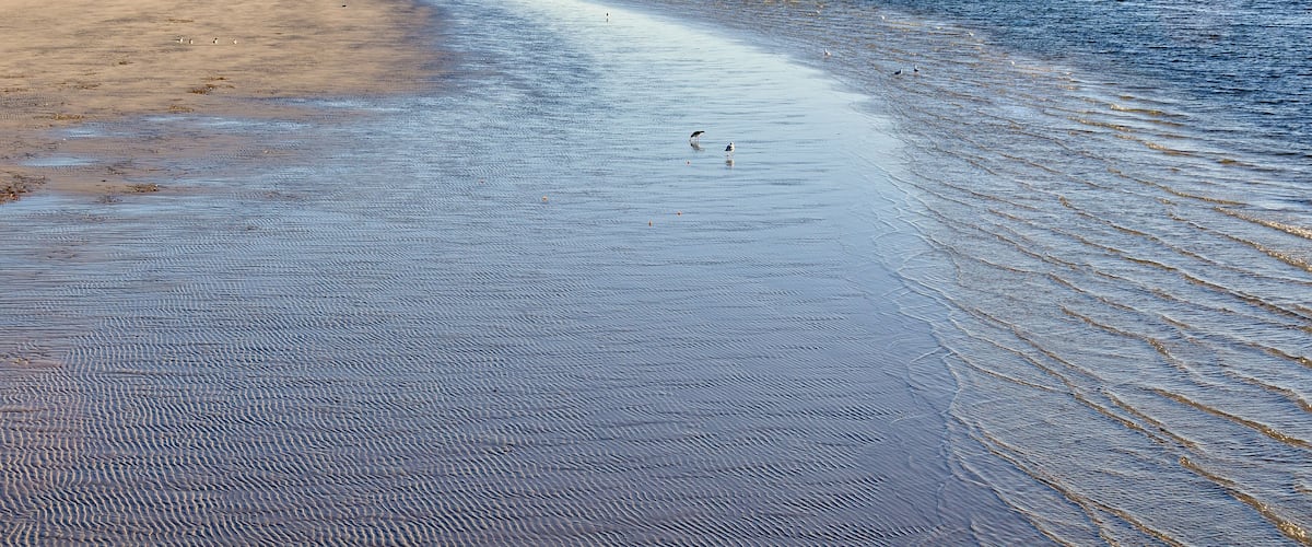 A wide sandy beach with gentle waves lapping at the shore.