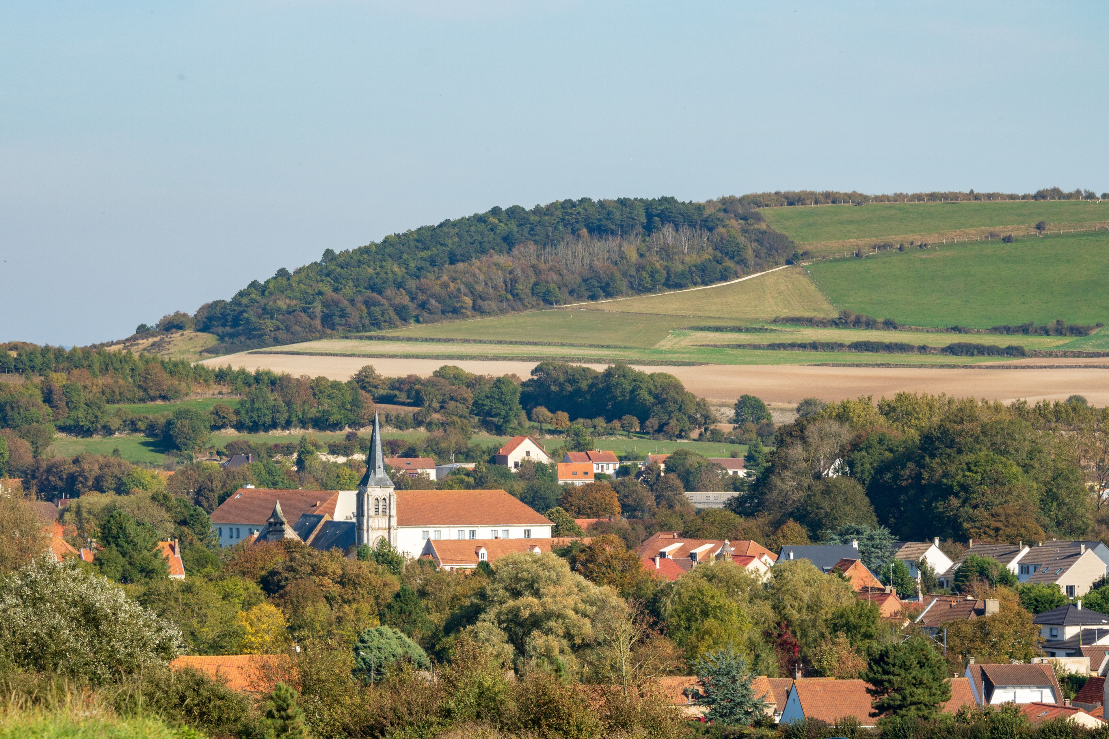 A rural village with a church, houses, and rolling hills.