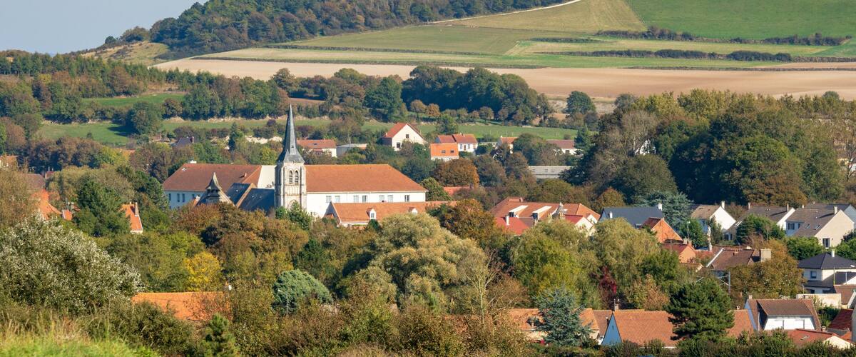 A rural village with a church, houses, and rolling hills.