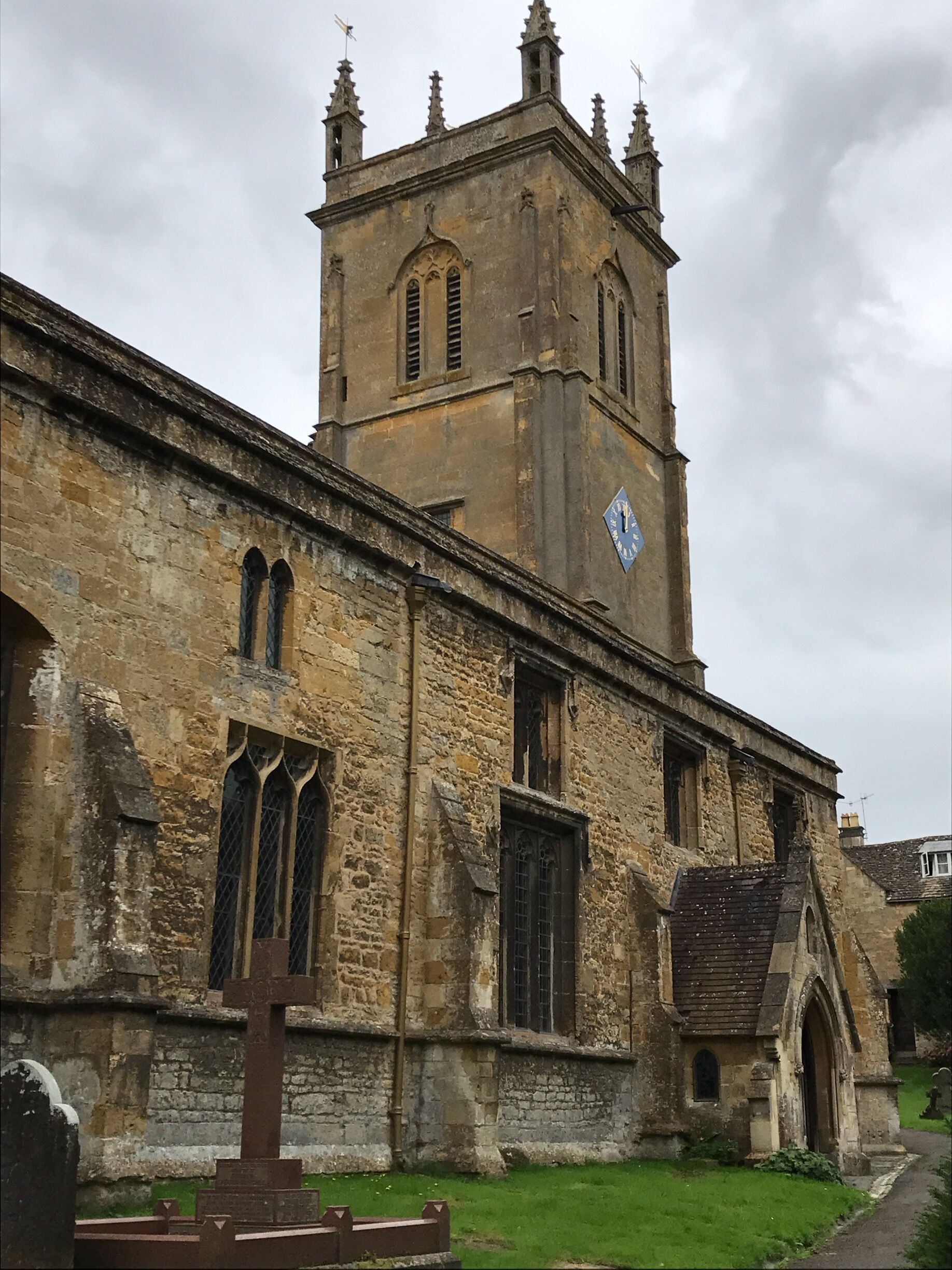 A historic stone building with a clock tower, arched windows, and a grassy courtyard.